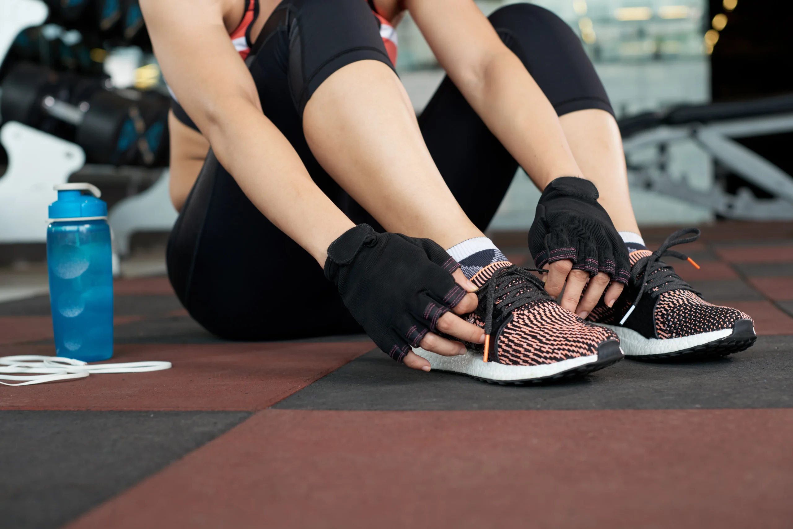 Mujer atándose las zapatillas deportivas en el gimnasio